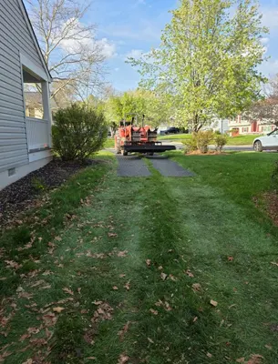 Tree trimming equipment parked on a residential lawn near a house.